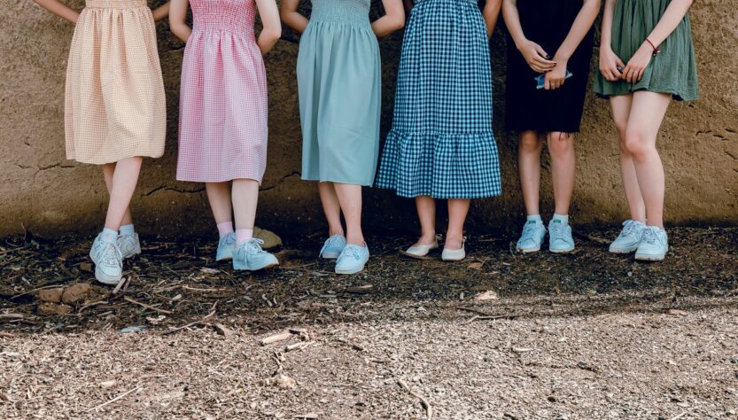 Kobiety w kolorowych sukienkach maja na stopach buty sportowe